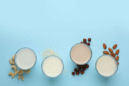 Different vegan milks, nuts and rice on light blue background, flat lay. Space for textの写真素材