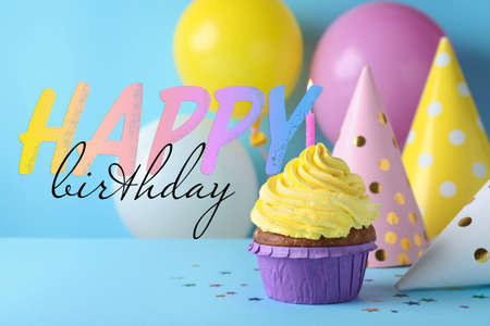Happy Birthday! Delicious cupcake with burning candle on light blue backgroundの写真素材