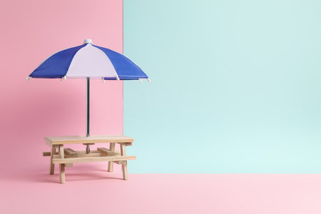Small wooden holder with toy umbrella on color background, space for textの写真素材