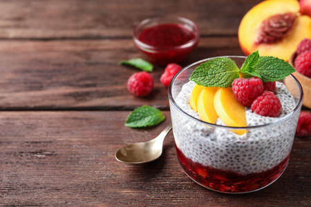 Delicious chia pudding with raspberries, peach and mint on wooden table, space for textの写真素材