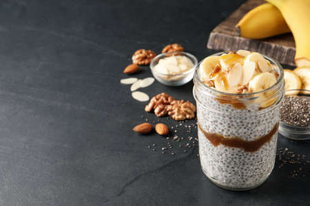 Delicious chia pudding with banana, walnuts and caramel sauce on black table, space for textの写真素材