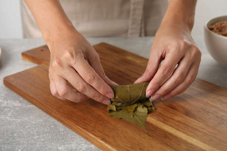 Woman preparing stuffed grape leaves at table, closeupの写真素材