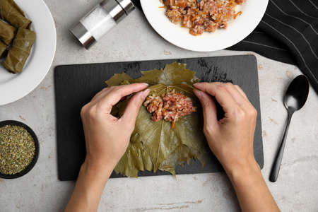 Top view of woman preparing stuffed grape leaves at light table, closeupの写真素材