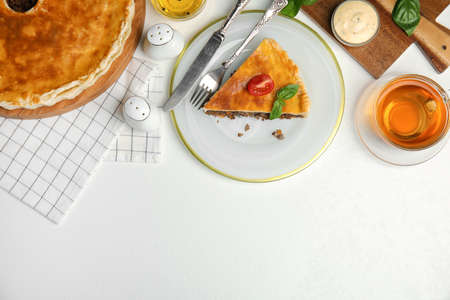 Delicious pie with minced meat, tomato and tea served on white table, flat lay. Space for text