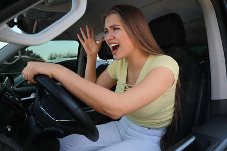 Emotional woman in car. Aggressive driving behaviorの写真素材