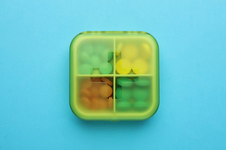 Pill box with medicaments on light blue background, top viewの写真素材