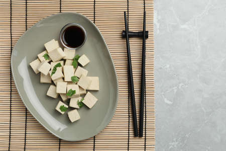 Delicious tofu with parsley, soy sauce and chopsticks on gray marble table, flat layの写真素材