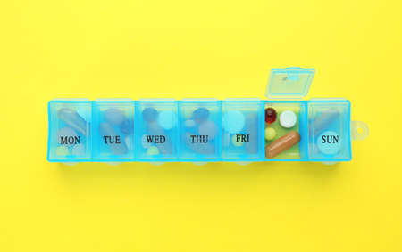 Pill box with medicaments on yellow background, top viewの写真素材