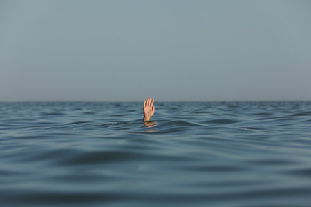 Drowning woman reaching for help in sea