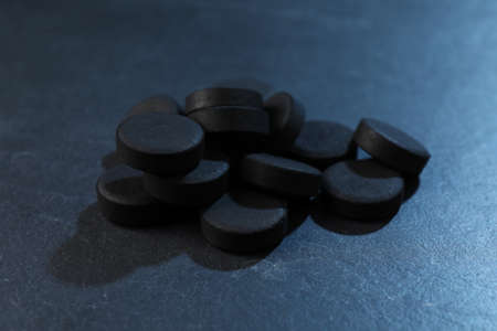Pile of activated charcoal pills on table, closeup. Potent sorbentの写真素材