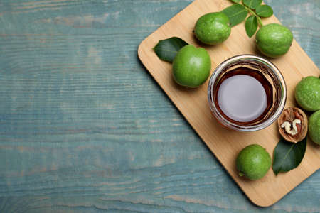 Delicious liqueur and fresh walnuts on light blue wooden table, top view. Space for textの写真素材