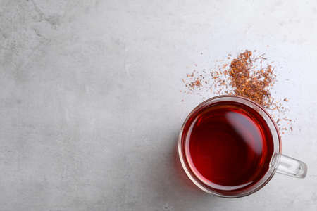 Freshly brewed rooibos tea and scattered dry leaves on gray table, flat lay. Space for textの写真素材