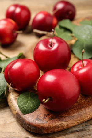 Delicious ripe cherry plums with leaves on wooden table, closeupの写真素材