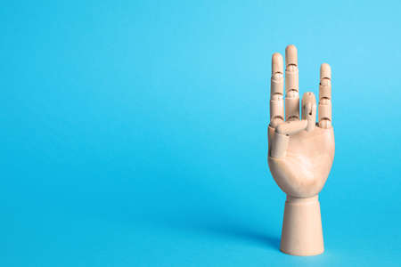 Wooden mannequin hand on light blue background. Space for textの写真素材