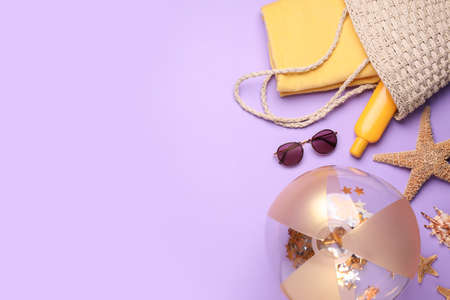 Flat lay composition with beach ball and other accessories on violet background. Space for textの写真素材