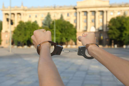 Woman in handcuffs on city street, closeup