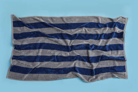 Crumpled striped beach towel on light blue background, top view