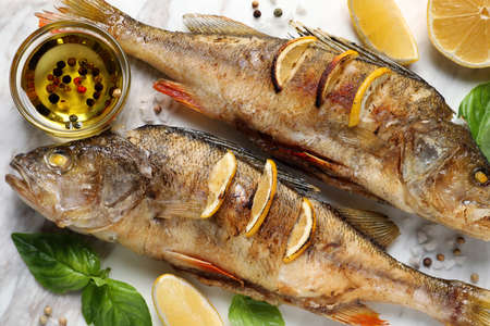 Tasty homemade roasted perches served on white board, flat lay. River fish