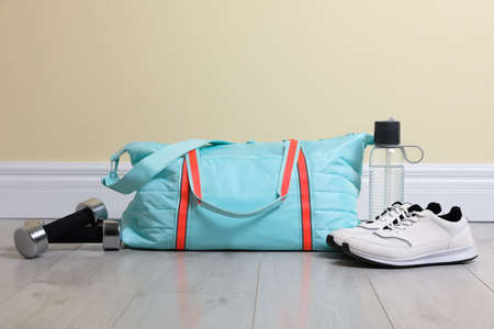 Bag with different sports equipment on wooden floor indoorsの写真素材