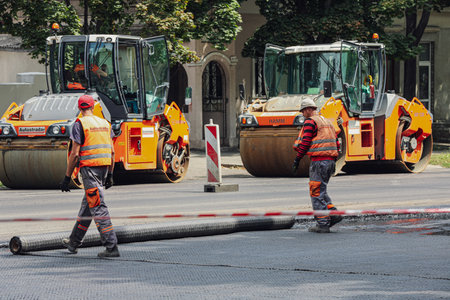MYKOLAIV, UKRAINE - AUGUST 04, 2021: Workers with road repair machinery laying new asphaltのeditorial素材