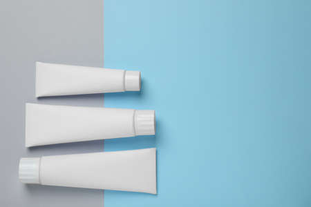 Blank tubes of toothpaste on color background, flat lay. Space for textの写真素材