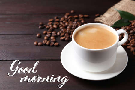 Cup of hot aromatic coffee and roasted beans on wooden table. Good morning