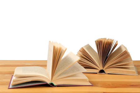 Open books on wooden table against white background. Library material