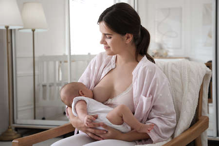 Young woman breastfeeding her little baby at home