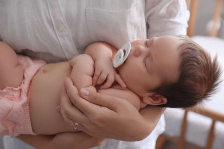Mother holding her cute little baby with pacifier at home, closeupの写真素材