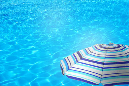 Open beach umbrella and swimming pool. Summer vacation