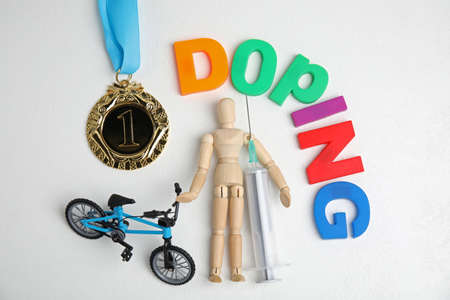 Word Doping, syringe, medal, sportsman and bicycle model on white table, flat layの写真素材