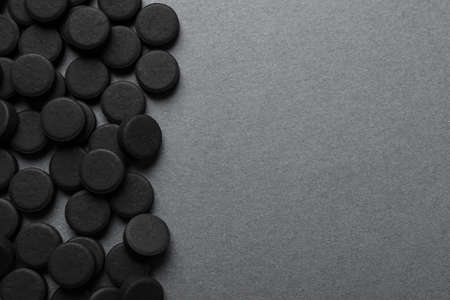 Activated charcoal pills on gray background, flat lay with space for text. Potent sorbentの写真素材