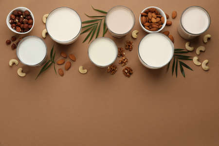 Different vegan milks and nuts on brown background, flat lay. Space for textの写真素材