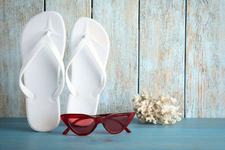Stylish flip flops, coral and sunglasses near wooden wallの写真素材