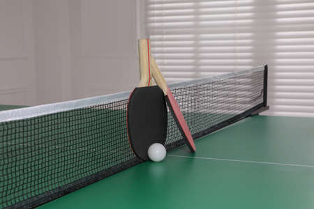 Rackets and ball on table tennis table indoors