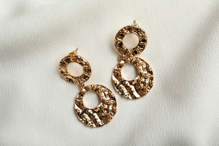 Elegant golden earrings on white fabric, flat lay. Stylish bijouterieの写真素材