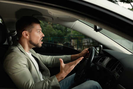 Stressed businessman in driver's seat of modern carの写真素材