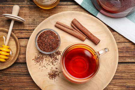 Freshly brewed rooibos tea, dry leaves and cinnamon sticks on wooden table, flat layの写真素材