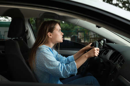 Stressed young woman in driver's seat of modern car