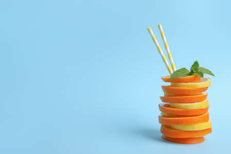 Stacked orange and lemon slices with straws as cocktail on light blue background. Space for textの写真素材
