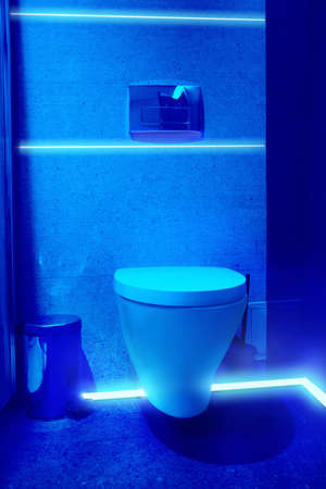 Toilet bowl in public restroom lit with UV blue lightの写真素材