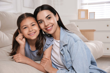 Young mother and her daughter on sofa in living room. Adoption conceptの写真素材