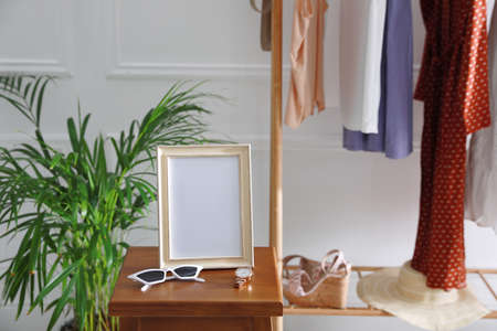 Empty photo frame, sunglasses and watch on wooden table indoorsの写真素材