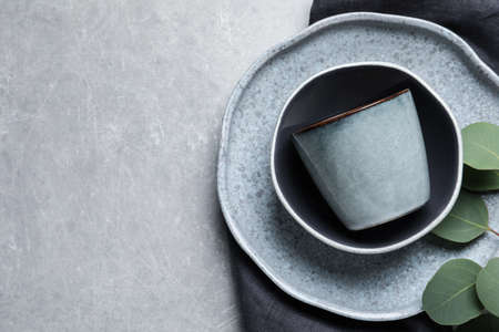 Set of dishware with eucalyptus leaves and napkin on gray table, flat lay. Space for textの写真素材
