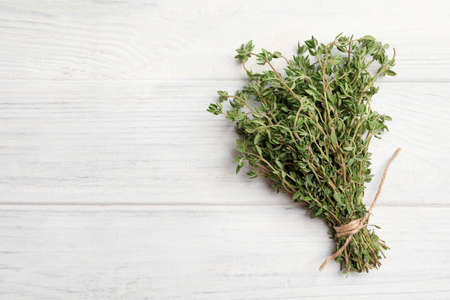 Bunch of aromatic thyme on white wooden table, top view. Space for text
