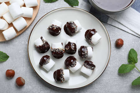 Delicious marshmallows covered with chocolate and on light table, flat lay