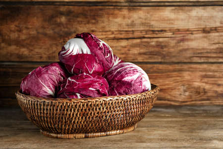 Fresh ripe radicchios in wicker basket on wooden tableの写真素材