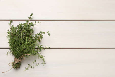 Bunch of aromatic thyme on white wooden table, top view. Space for textの写真素材