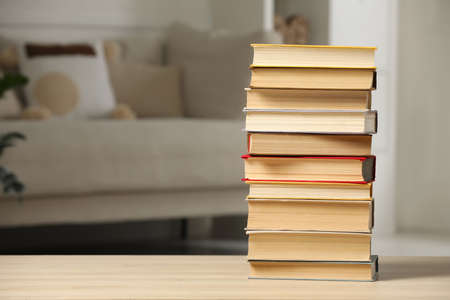 Stack of books on wooden table in living room, space for text. Home libraryの写真素材