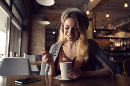 Young woman with cup of coffee at cafe in morningの写真素材